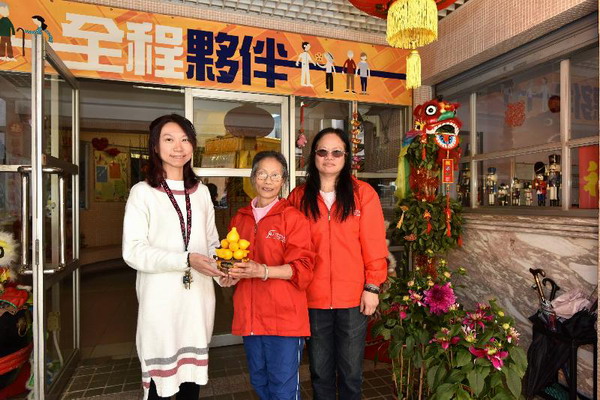 食環署義工隊成員把一盆由年宵市場花檔檔主送出的年花,轉送到一間安老院的代表手上。