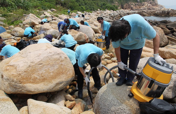 Staff of the Food and Environmental Hygiene Department (FEHD) clear plastic pellets at Shek Pai Wan on Lamma Island with vacuum cleaners today (August 9).
