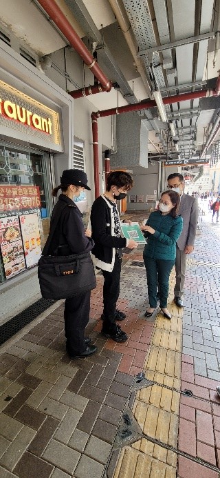 食環署副署長(環境衞生)黃淑嫻女士在深水埗區香港盲人輔導會附近向餐飲處所負責人派發凸字膠套並講解用法