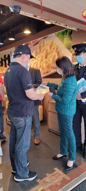 食環署副署長(環境衞生)黃淑嫻女士在觀塘區香港失明人互聯會附近向餐飲處所負責人派發凸字膠套並講解用法